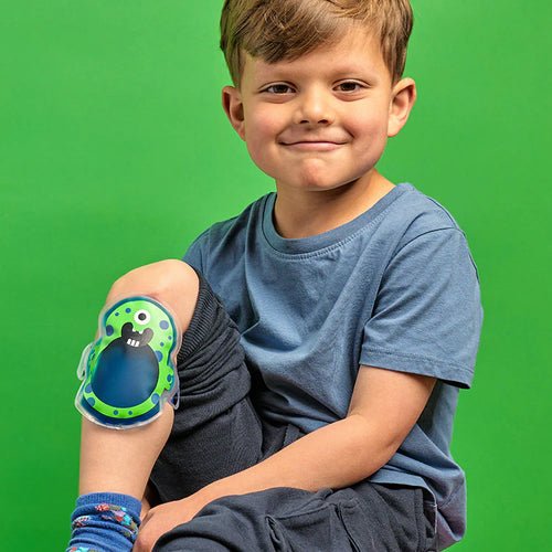 Child with a colorful cold pack on their leg against a green background