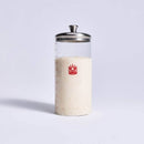 Clear glass container with a metal lid and red logo filled with sourdough on a light gray background