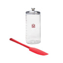Clear measuring container with silver lid and red spatula on a white background