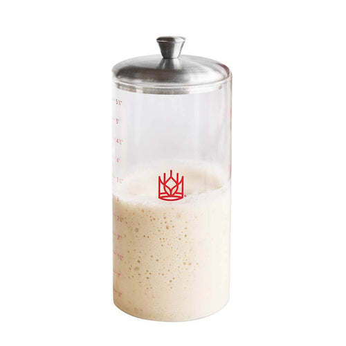 Clear container with a metal lid filled with sourdough on a white background