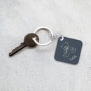 Keychain with teddy bear design and engraved name on a textured surface