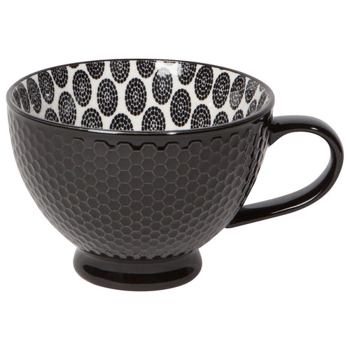 A black porcelain latte mug with a dotted pattern on the inside and a solid black color in a mini honeycomb pattern on the outside.