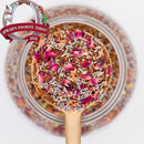 Spoonful of dried tea leaves and flowers over a jar with 'Oprah's Favorite Things 2021' label.