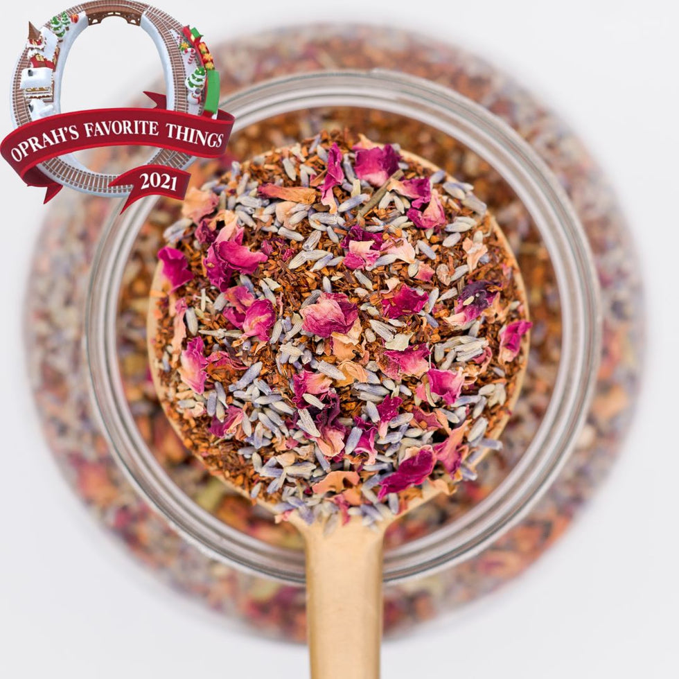 Spoonful of dried tea leaves and flowers over a jar with 'Oprah's Favorite Things 2021' label.