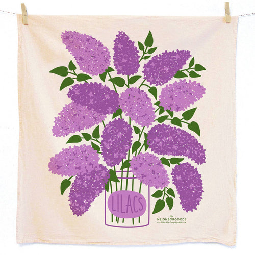A dish towel with lilac illustration clipped to a clothesline with clothespins on a white background.