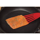 Salmon fillet on a frying pan with a red spatula