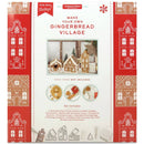 Packaging for 'Make Your Own Gingerbread Village' kit, featuring an image of a gingerbread village with cottages, townhouses, and chalets, along with a list of included cookie cutters and tools.