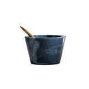 Blue-gray marble bowl with a gold spoon on a white background