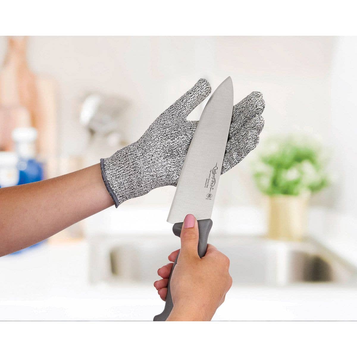 Person holding a knife with a protective glove in a kitchen setting