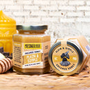 Two jars of Messner Bee Farm creamed honey on a textured surface.