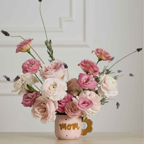 Floral arrangement in a mug with 'Mom' text on a neutral background