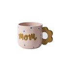 Pink mug with 'mom' text and floral handle on a white background
