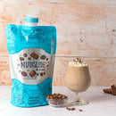 Mudslide cocktail mix in a bag with a glass of cocktail and ingredients on a wooden background
