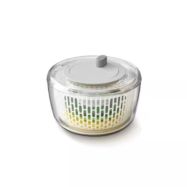 A clear salad spinner with other components inside and a gray lid on a white background.