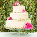 A three-layer cake with floral decorations and foliage in the background.