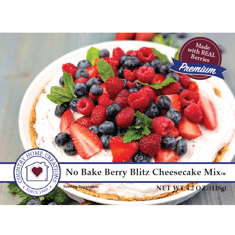 No Bake Berry Blitz Cheesecake Mix packaging and prepared dessert presentation. A white plate holds a cheesecake topped with mixed berries, strawberries, blueberries, raspberries, mint leaves, and graham cracker crumbs.