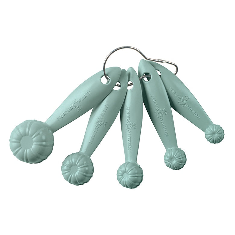 Set of five light blue measuring spoons on a white background