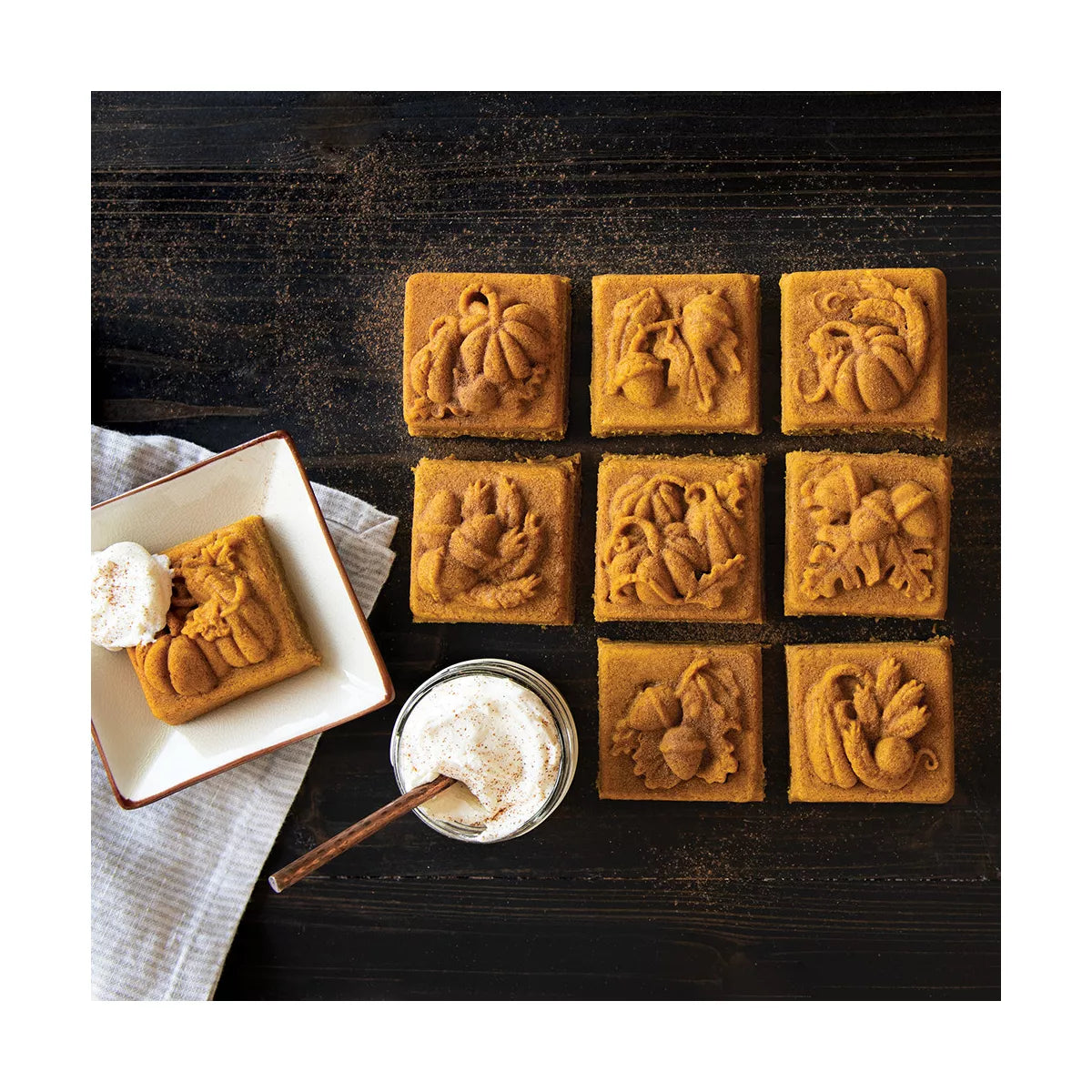 Decorative cookies with intricate designs on a dark surface, accompanied by a bowl of whipped cream.