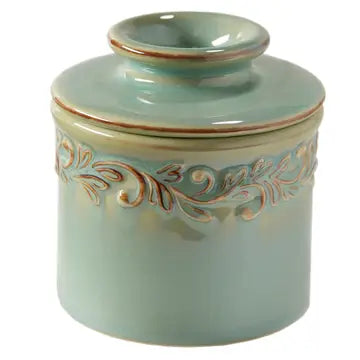 A green ceramic Butter Bell crock with intricate leaf embossing.