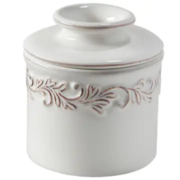 A white ceramic Butter Bell crock with intricate leaf embossing.