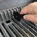 Person using a black tool to clean a grill grate