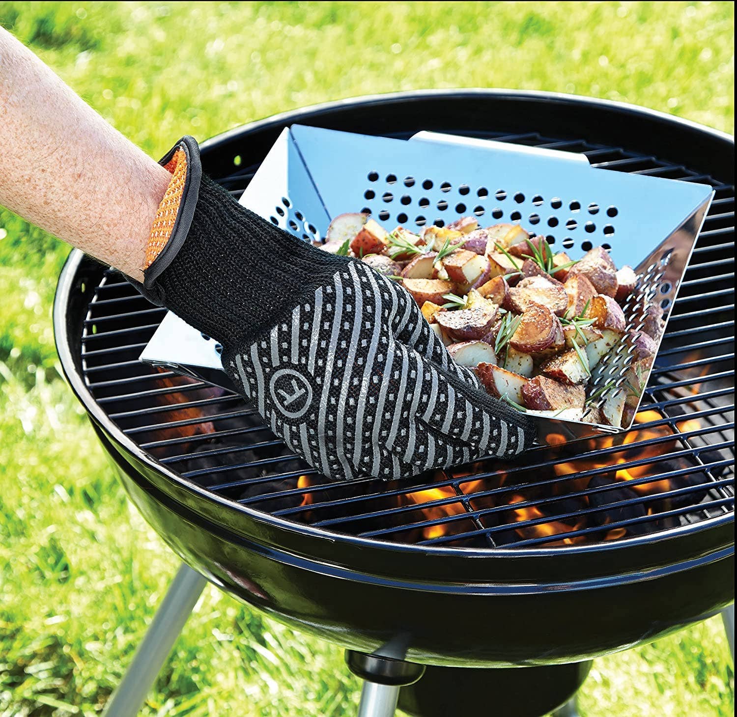 Person using a grill glove to handle food on a barbecue grill outdoors.