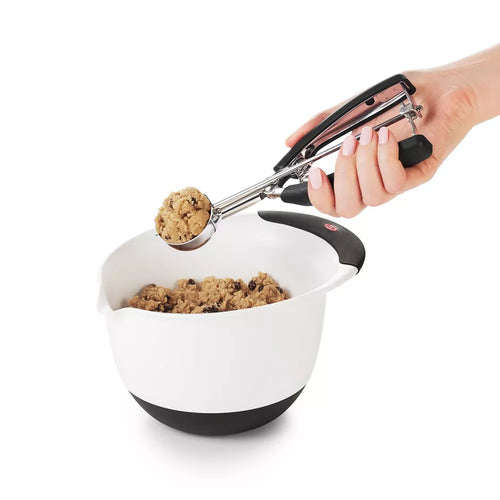 Cookie dough being scooped out of a bowl using a cookie scoop.