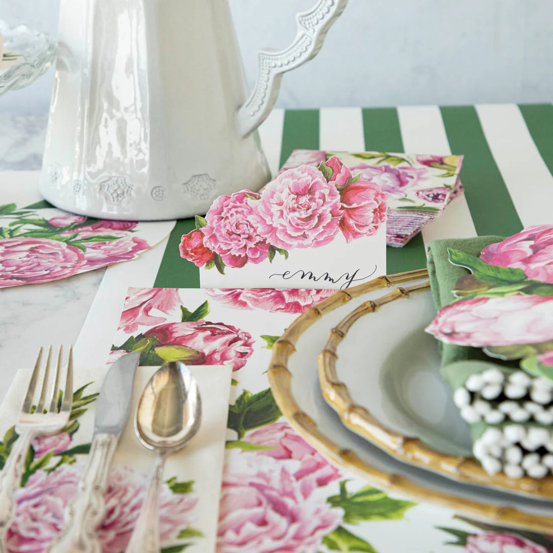 A place setting with silverware, peony placemats, and a peony name card.