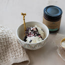 Bowl of ice cream with peppermint fudge on a light surface next to a jar of peppermint fudge.