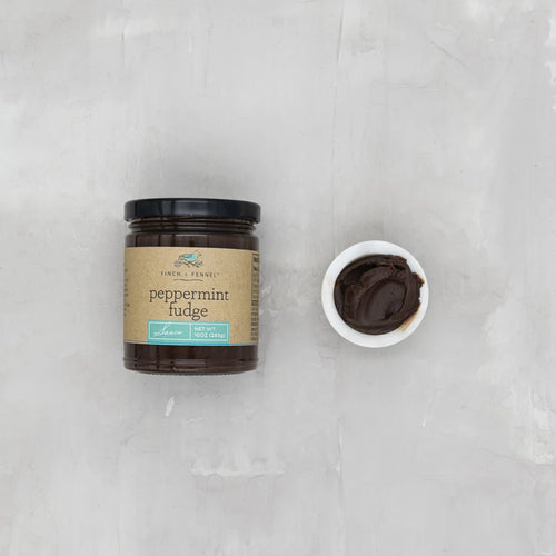 Jar of peppermint fudge with a small bowl of fudge on a gray background