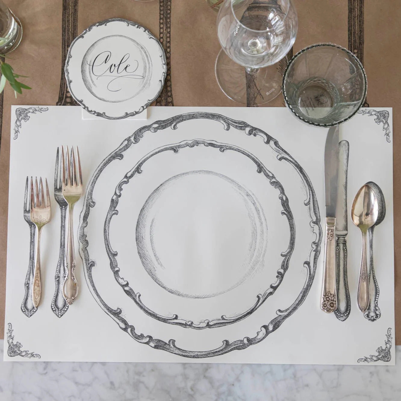 Silver and white place setting on a marble surface.