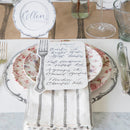 Plates and flatware on a placemat with menu card and place card.