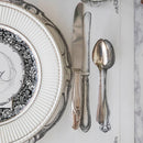 A close up of a plate, knife, and spoon on a paper placemat that features illustrations of a place setting.