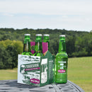 A case of Pioneer Spring Sparkling Water glass bottles placed on a table with a field in the background.