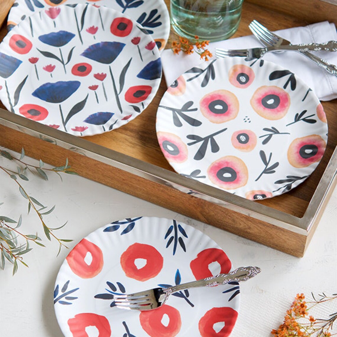 Floral-patterned plates on a wooden tray with utensils.