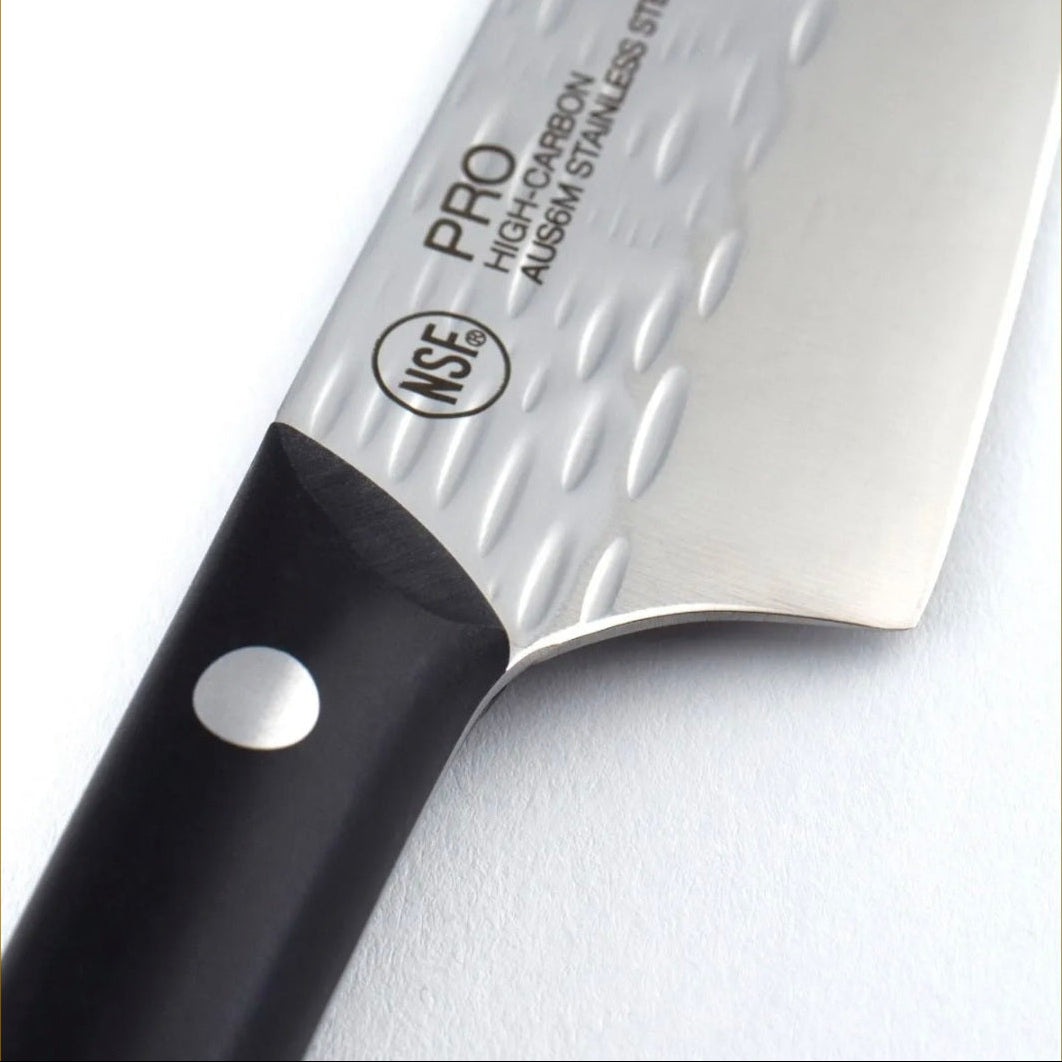 A close-up of a kitchen knife with a textured silver stainless steel blade and a black handle, featuring the NSE PRO logo and AUSM stainless steel text on the blade.