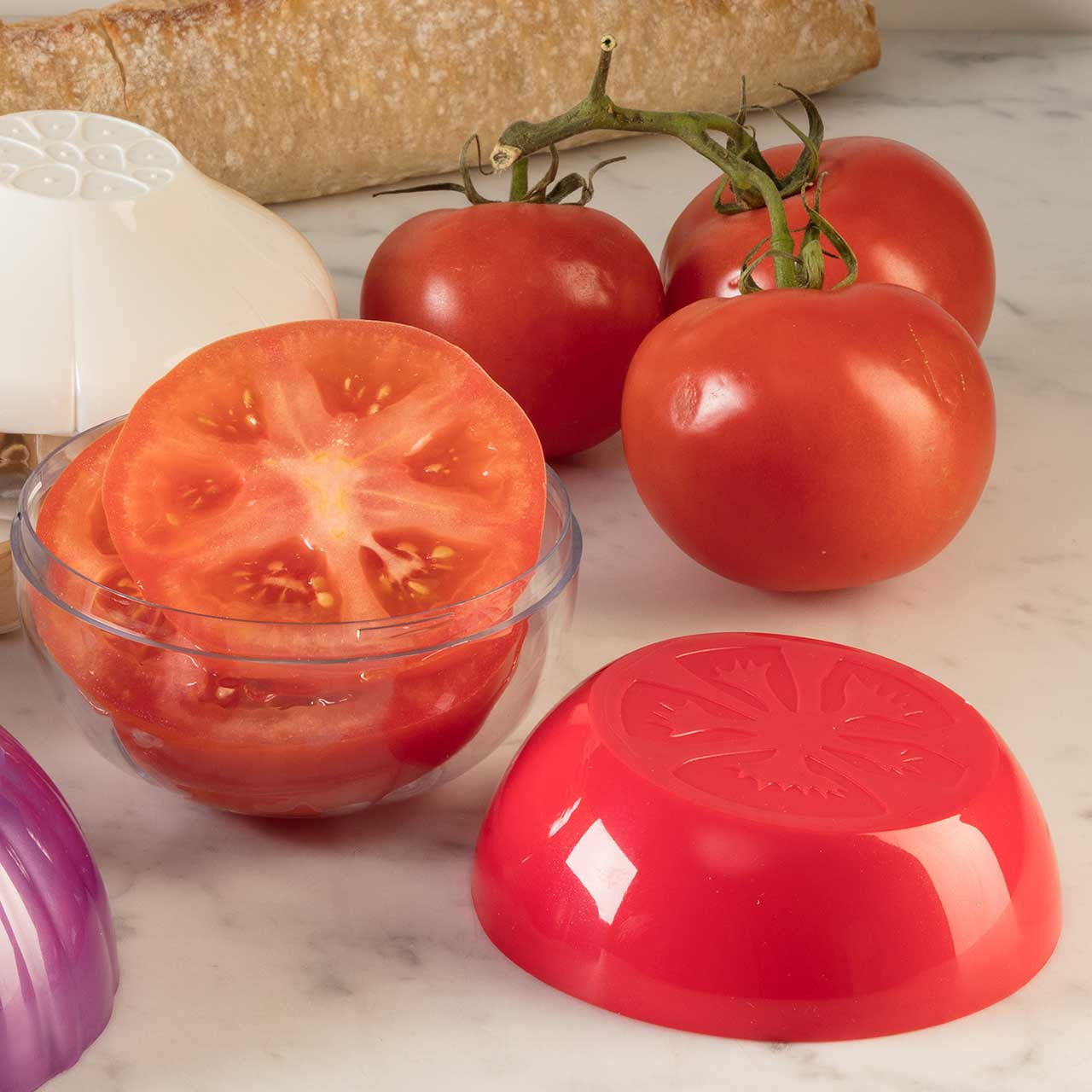 Tomatoes with a sliced tomato in a clear container and a red lid on a marble surface.