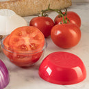 Tomatoes with a sliced tomato in a clear container and a red lid on a marble surface.