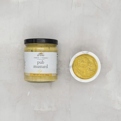 Jar of pub mustard with a small bowl of mustard on a light gray background