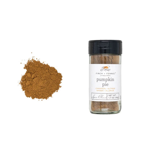 Bottle of pumpkin pie spice with a small pile of spice beside it on a white background.