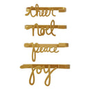 A set of four gold-colored napkin holders with the words 'Cheer', 'Noel', 'Peace', and 'Joy' inscribed on them.
