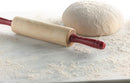 Wooden rolling pin with red handle on a marble surface next to a ball of dough.