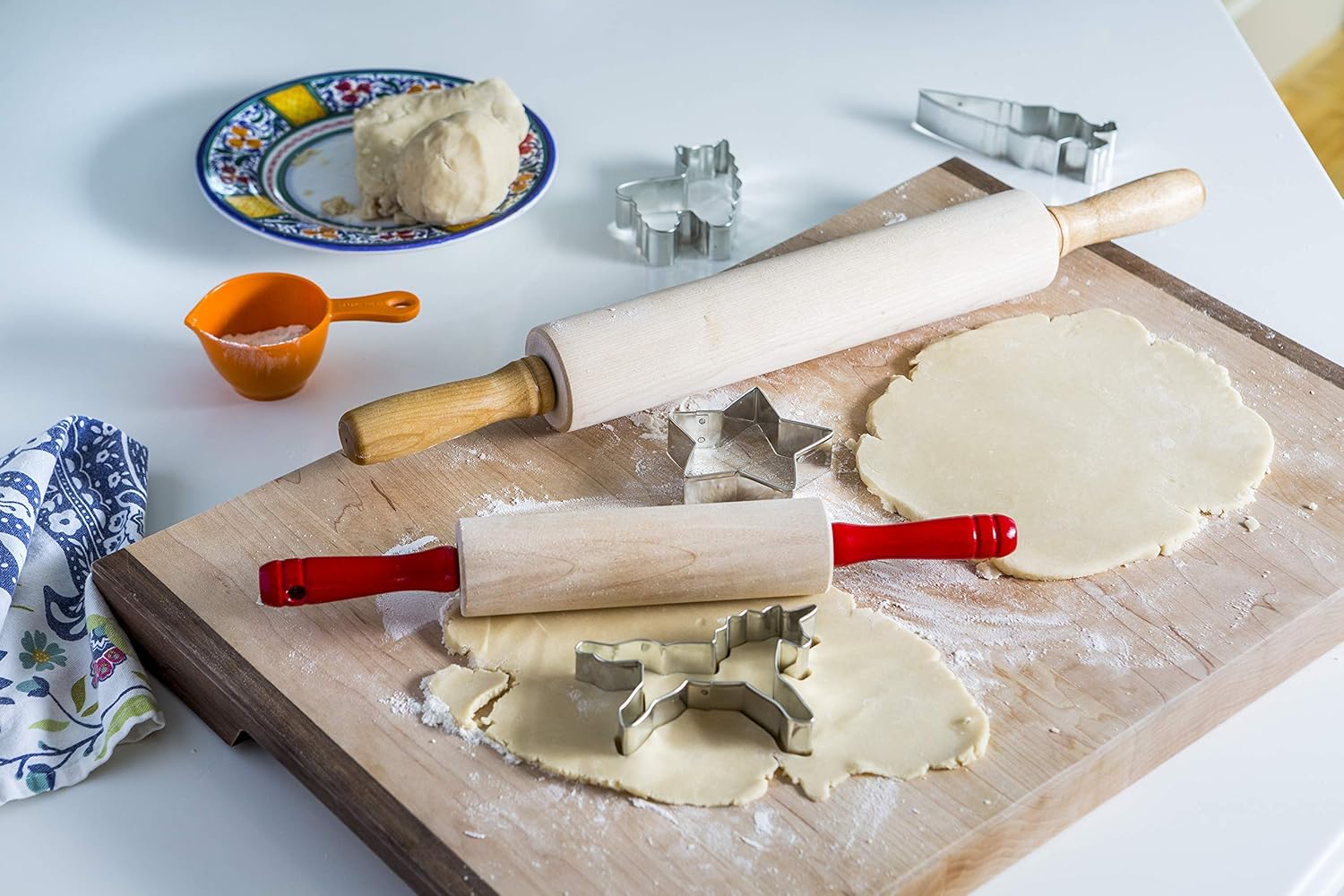Baking setup with rolling pins, cookie cutters, and dough on a wooden board.