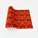 A red table runner with a geometric pattern of orange and navy poppies displayed on a white background.