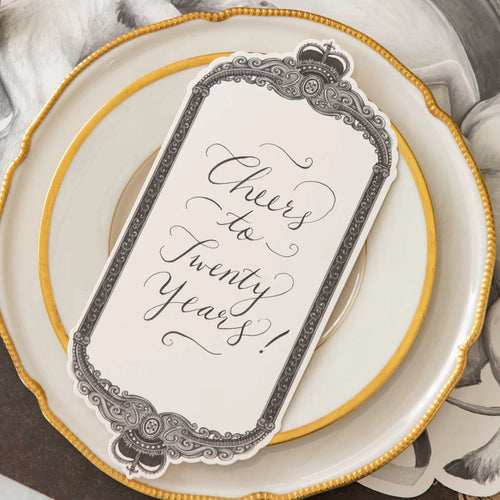 Decorative place card with 'Cheers to Twenty Years!' text on a gold-rimmed plate.