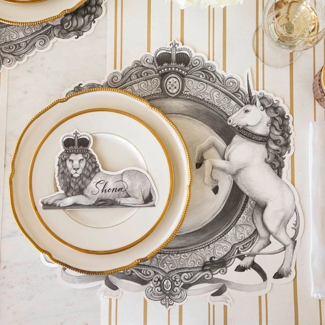 A place setting featuring regal unicorn placemat and lion wearing a crown place card.