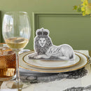 A regal lion wearing a crown place card on a pair of plates with a glass of wine.