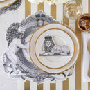 A place setting featuring regal lion placemat and lion wearing a crown place card on a gold and white striped table runner.