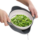 Person holding a colander with green beans against a white background
