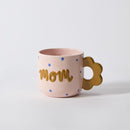 Pink mug with 'Mom' text and flower handle on a white background